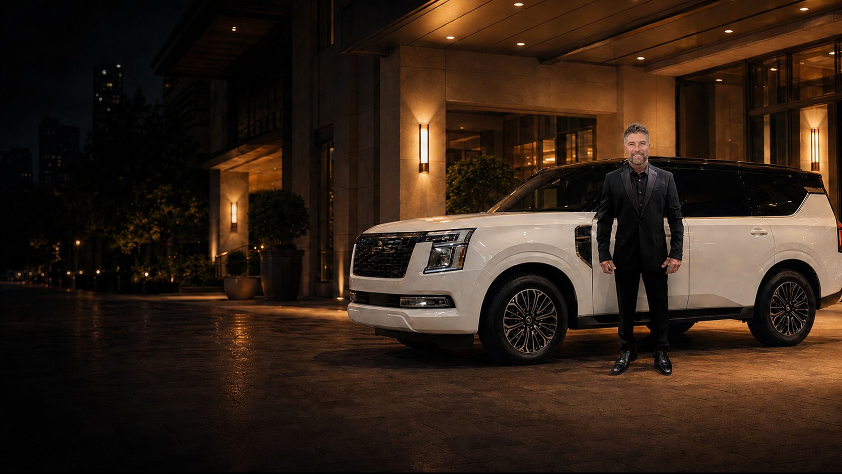 Antonio D’Armiento beside his white Nissan Armada at an elegant hotel entrance